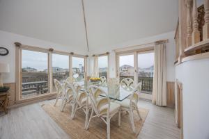 a dining room with a table and chairs and windows at 1067 - Easy Street in Corolla +41 photos