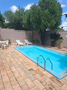 a swimming pool with two chairs and a table at Suíte até 3 pessoas, Centro, Piscina in Foz do Iguaçu