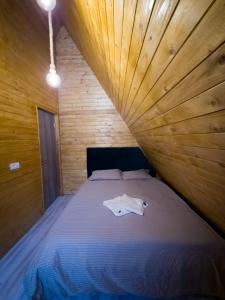 a bed in a room with a wooden wall at Cabana Z-Haven in Ungureni
