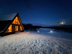 a log cabin in the snow at night at Cabana Z-Haven in Ungureni
