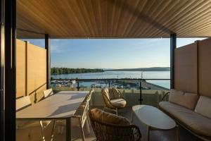 a balcony with a couch and a table and chairs at La Capitainerie du Lac-Mégantic in Lac-Mégantic