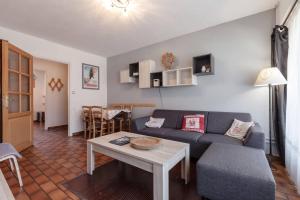 uma sala de estar com um sofá azul e uma mesa em T3 avec terrasse plein sud au pied des télécabines em Briançon