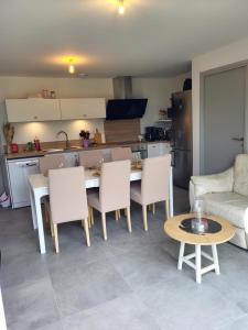 a living room with a table and chairs and a kitchen at Gîte Bord De Mer La Guichardière in Pirou