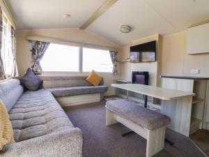 a caravan living room with a couch and a table at Dunes View in Prestatyn