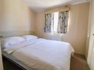 a bedroom with a white bed and a window at Dunes View in Prestatyn