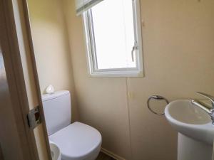 a bathroom with a toilet and a sink and a window at Dunes View in Prestatyn +21 photos