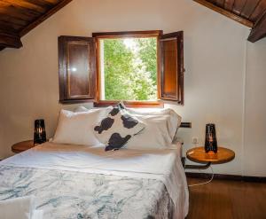 a bedroom with a bed with a window and two tables at Casa do Batoco in Vieira do Minho