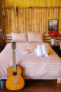 a guitar is sitting on a bed with a guitar at Làng Hương Village in Teurnoum