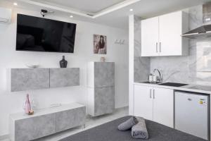 a kitchen with white cabinets and a tv on the wall at Ocean View Ponderosa 601 Costa Adeje Playa de las Americas in Costa de Adeje +3 photos