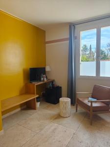 a living room with a yellow wall and a window at La Maison des Ocres - Provence in Roussillon