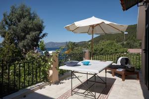 a white table with an umbrella and a chair at Anassa Boutique Beach House in Sami