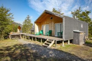 a wooden cabin with green chairs on a dock at Piedra Nevada in Malalcahuello