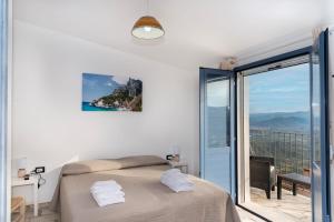 a white bedroom with a bed and a balcony at B&B Golgo in Baunei