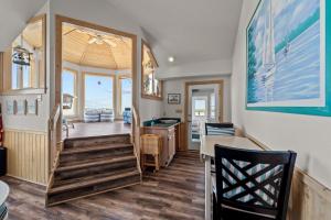 a living room with a staircase leading to a dining room at 3945 - Sea Lodge II in Duck +55 photos