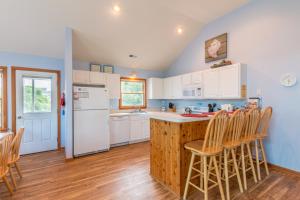 a kitchen with white cabinets and a counter with chairs at 3944 - Carolina Escape in Duck +30 photos