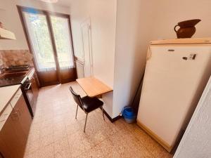 a kitchen with a refrigerator and a table and a chair at Le Petit Ousson Studio avec Jardin in Briare +1 photo