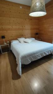 a bedroom with a white bed with a wooden wall at Piccolo Appartamento Casa Vacanze B&B Angela in Clusone