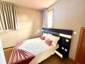 a bedroom with a bed with pink pillows and a window at Residencial Portas do Sol in Valença