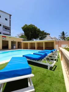 a row of blue lounge chairs next to a swimming pool at Ntate Homes, Diani Near the Beach in Diani Beach