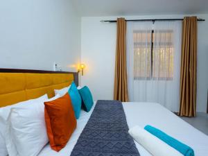 a bedroom with a large bed with colorful pillows at Ntate Homes, Diani Near the Beach in Diani Beach +29 photos