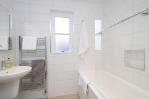 a white bathroom with a tub and a sink at Manuka Cottage in Aviemore