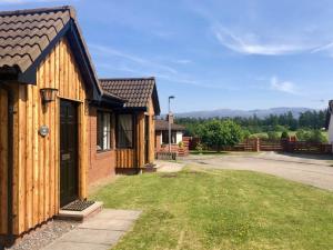 a building with a grass yard next to a house at Manuka Cottage in Aviemore +4 photos