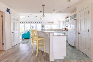 a kitchen with white appliances and yellow stools at a counter at 4751 - Purple Passion in Kitty Hawk Beach +30 photos