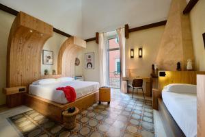 a bedroom with two beds and a desk and a window at Mamaco Trani in Trani