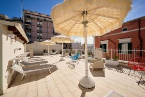 a patio with umbrellas and chairs on a building at Mamaco Trani in Trani