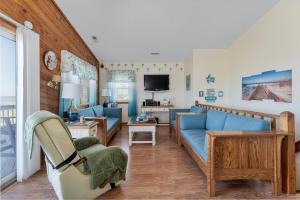 a living room with a blue couch and a tv at 4785 - Paradise Found in Kitty Hawk