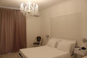 a bedroom with a white bed and a chandelier at Hotel Imperiale in Terzigno