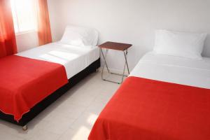 two beds with red and white sheets in a room at Miss Leila in San Andrés