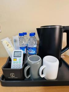 a tray with a coffee maker and cups and water bottles at Cactus Hotel in Dar es Salaam