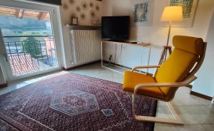 une chaise jaune dans un salon avec une télévision dans l'établissement Bed&Breakfast Angela, à Clusone