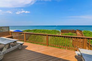 a deck with a picnic table and chairs on the beach at 5437 - WeekAway in Nags Head