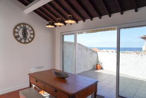 a room with a table and a clock on the wall at Canto 30 e UM - HOST & CHILL in Ribeira Grande