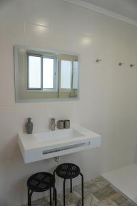 a bathroom with a sink and a mirror and two chairs at Canto 30 e UM - HOST & CHILL in Ribeira Grande +39 photos
