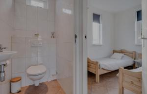 a bathroom with a toilet and a sink and a bed at Huisje Britt met grote tuin en veel privacy in Dirkshorn +49 photos