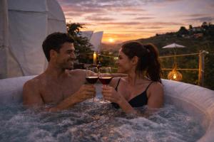 a man and woman in a bath tub with glasses of wine at Origen Glamping en Villa de Leyva in Villa de Leyva
