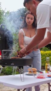a man and a woman cooking food on a grill at Origen Glamping en Villa de Leyva in Villa de Leyva