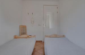 two beds in a room with white walls at Huisje Britt met grote tuin en veel privacy in Dirkshorn