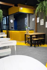 a restaurant with tables and chairs and a yellow wall at Free Way Kata Beach Hostel in Kata Beach
