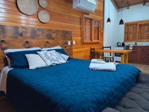 a bedroom with a blue bed with a wooden wall at Aconchego da Serra in São Joaquim