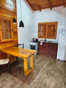 a kitchen with a wooden table and a refrigerator at Aconchego da Serra in São Joaquim