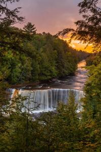 a waterfall in the middle of a river with trees at Adventure & Relaxation by Lake Superior in Paradise