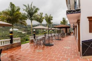 a patio with tables and chairs and palm trees at Ecohotel Dubai del Oriente in El Peñol