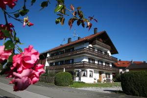 a large building with a roof with pink flowers at Pension Maria in Antdorf