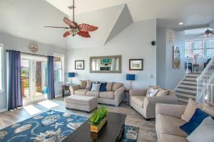 a living room with couches and a ceiling fan at 5469 - Below Deck OBX in Nags Head