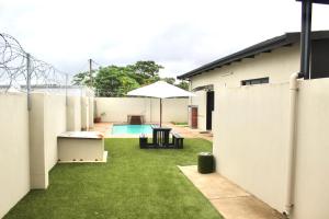 a backyard with a pool and an umbrella at B&B Hotel Esikhaleni in eSikhawini