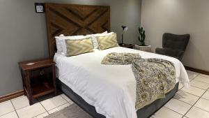 a bedroom with a bed with a blanket and a chair at Dessert Rose Guesthouse in Jwaneng +18 photos